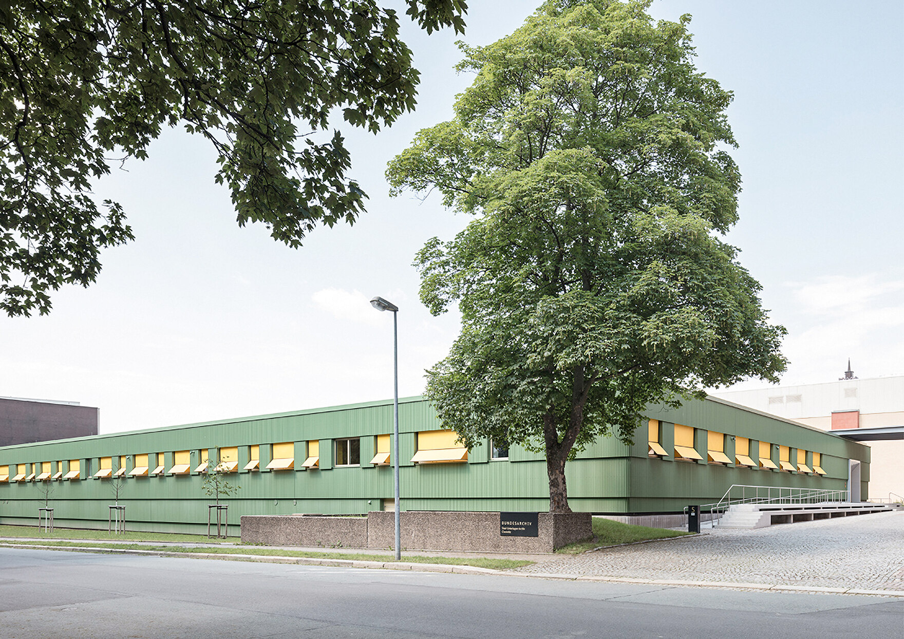 Bild eins grünen Gebäudes mit einem Baum im Vordergrund