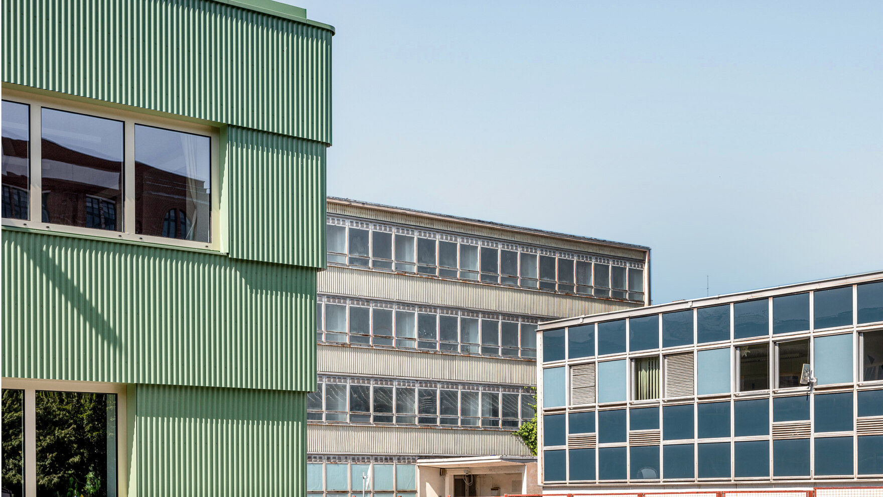 Drei unterschiedlich farbige Industriegebäude vor blauem Himmel