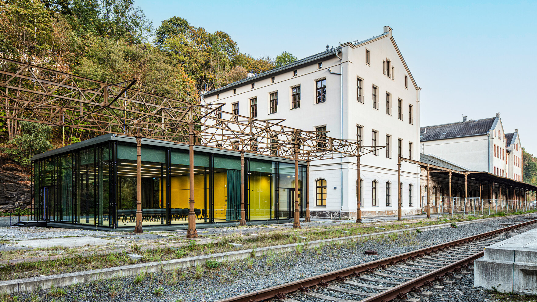 Bahnhof mit Metallsäulen und modernem Glasbau neben historischem Gebäude